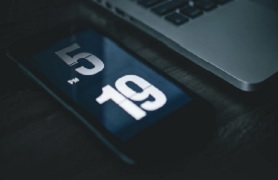 Phone displaying 5:19 by laptop 